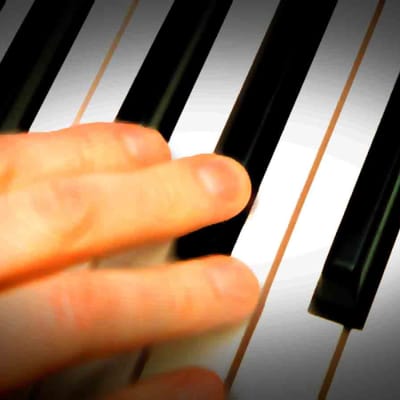 pianon koskettimisto ja käsi lähikuvassa