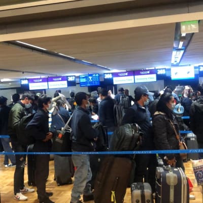 En stor grupp asiatiska resenärer med munskydd på flygplats.