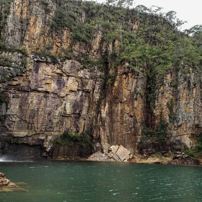 En hög bergsvägg vid en konstsjö i Brasilien, en del av väggen rasade ner över båtar. 