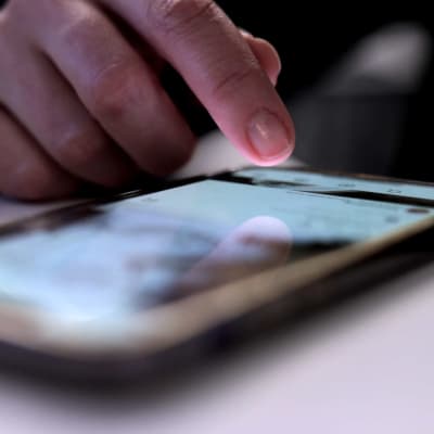 Närbild på ett finger på en smarttelefon. 