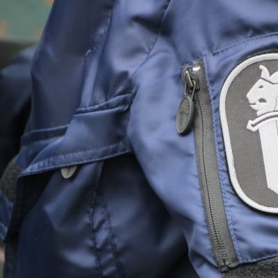 Poliisin logo poliisimiehen hihassa.