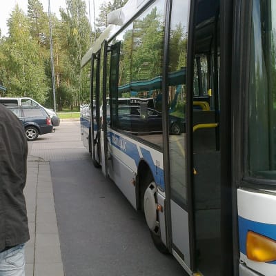 Bussi kuljettaa väkeä Renesasin tiedotustilaisuuteen