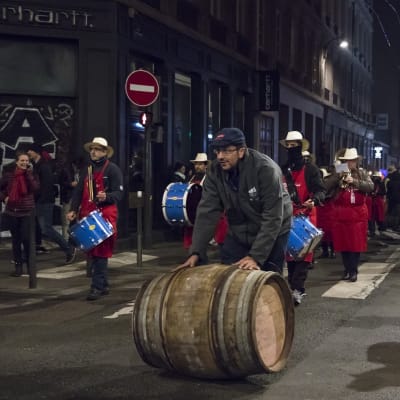 Viinitynnyrit vieritetään juhlasaattueessa Lyonin keskustaan juuri ennen puoltayötä.