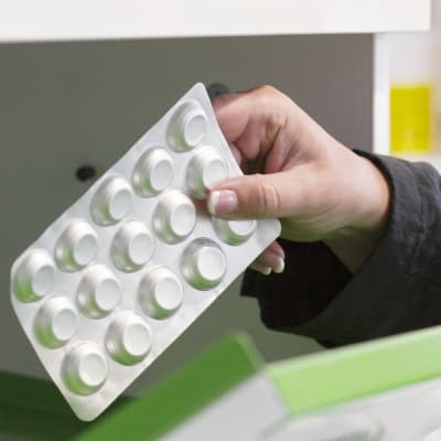 En person tar ut läkemedel ur ett skåp på ett apotek.