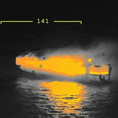 Ett fartyg upplyst i knallgult på enärmekamerabild av det brinnande biltransportfartyget Fremantle Highway.