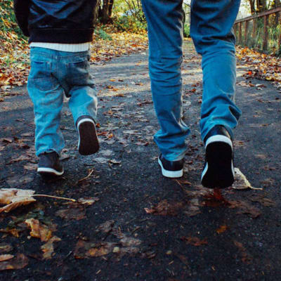 Benen på en pappa och en liten pojke på promenad.