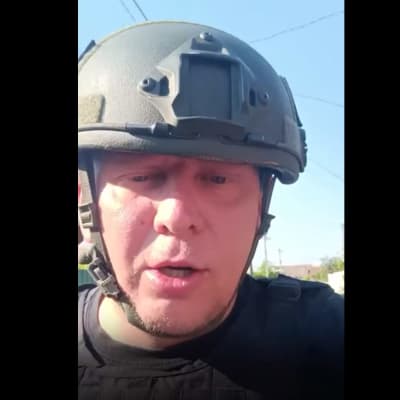 Kuvakaappaus videolta, jossa sotilaskypäräinen mies puhuu kameralle.