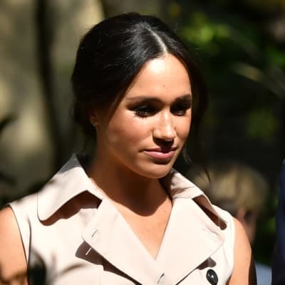 Herttuatar Meghan ja prinssi Harry kävelevät vierekkäin osin varjossa.