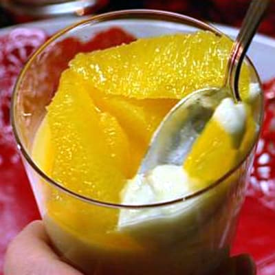 Ett glas med pannacotta och apelsinklyftor.