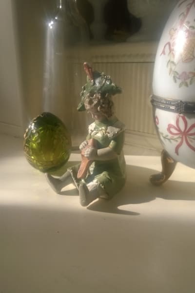 Ett grönt glasägg och en porslinsfigurin.