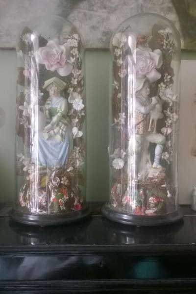 Två glasklockor från 1800-talet med skulpturer i.