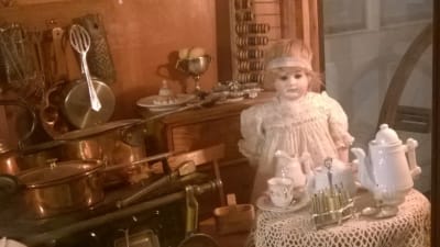 en antik docka sitter vid ett bord med te-dukning