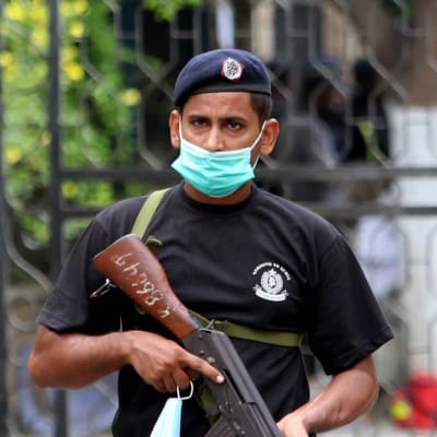 En militär bär munskydd utanför börsen i Karachi. Han håller i ett vapen. I bakgrunden ses fler militärer.