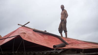 En man på en pressenning på ett tak.