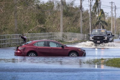 Bilar som försöker köra längs med översvämmade vägar.