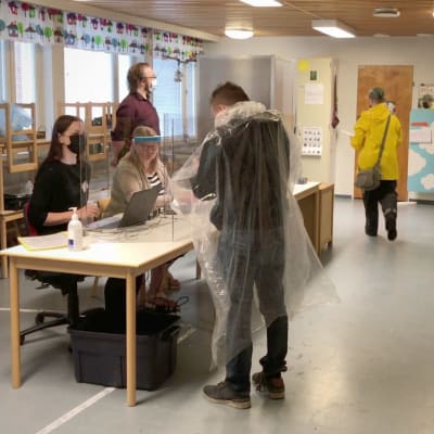 Ihmisiä sadevaatteissa äänestyspaikalla Joensuulaisessa päiväkodissa.