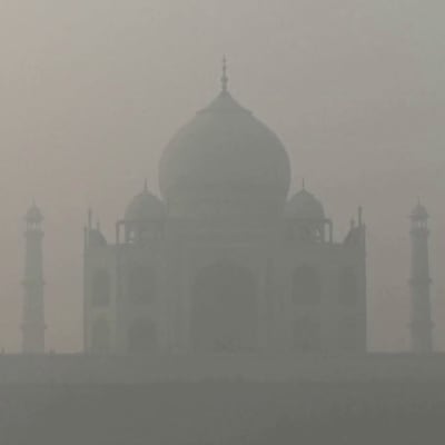 Taj Mahal syns som en skugga genom ett tjockt grått dis.