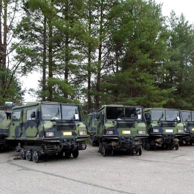 Pitkä rivi telakuorma-autoja isolla asfalttipihalla.