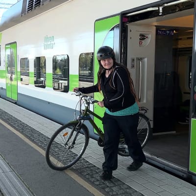 Minna Sirkiä tulee lähijunasta pyörän kanssa asemalaiturille.
