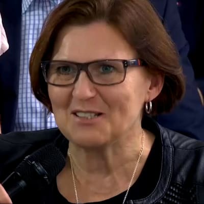 En kvinna med mikrofon framför sig.