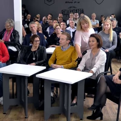 Flera människor sitter i publiken under en debatt.
