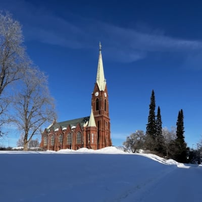 Mikkelin tuomiokirkko talvisessa maisemassa. aurinko paistaa.