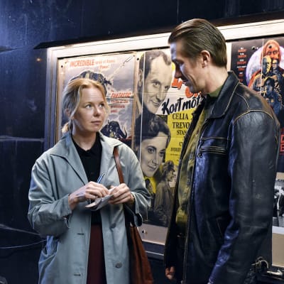 Bild från filmen Kuolleet lehdet. En kvinna och en man står framför en vägg med afficher.