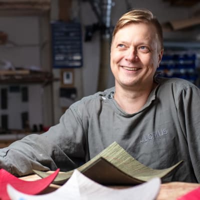 Ville Naumanen istuu puusepänverstaalla, etualalla puuesineitä.