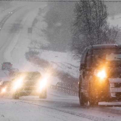 Autoja maantiellä lumisateessa.