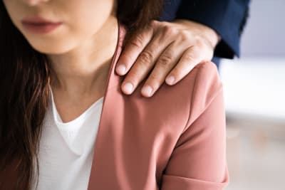En man håller sig hand på en kvinnas axel.