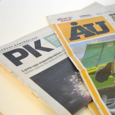 Tidningarna ÅU och Pargas kungörelser på ett bord.