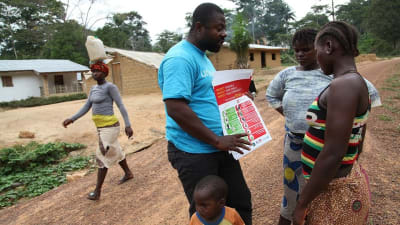 En FN-anställd berättar för några invånare i Liberia hur man undviker ebola.