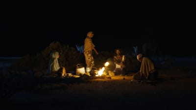 Personer samlade runt en lägereld på natten i filmen Guled & Nasra.
