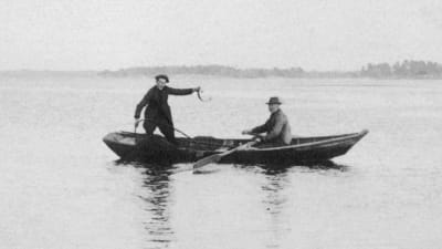 traditionellt nätfiske, två män står i en båt och vittjar nät.