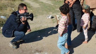 Antti Kuronen på knä med tv-kamera talar med flyktingbarn i Turkiet.