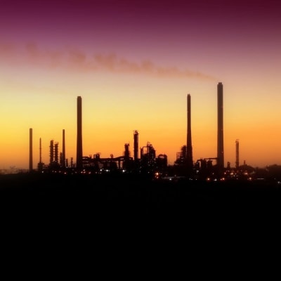 Tiotals fabrikspipor i vacker solnedgång med dis i luften