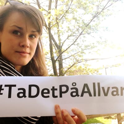 Selfie av Eva-Maria Koskinen med en #TaDetPåAllvar lapp