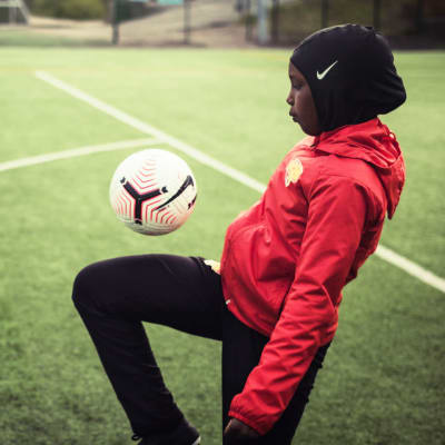 Jalkapalloa pelaava tyttö.