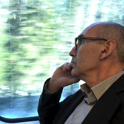 Juha T. Hakala istuu junassa ja tuijottaa ulos ikkunasta. 