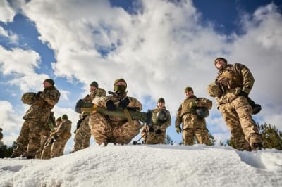 Ukrainska soldater i uniformer och utrustning står samlade och tittar framåt.