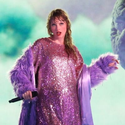 Taylor Swift står på en scen med mikrofon i handen medan hon uppträder.