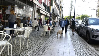 Folk sitter vid en uteservering i Lissabon.