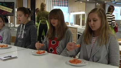 Tre tjejer smakar på tomat er