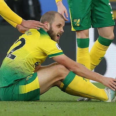 Teemu Pukki håller om sin fot och får stöd av lagkamrater.