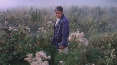 Mies seisoo niityllä mustassa takissa, kuva Andrei Tarkovskin elokuvasta Solaris.