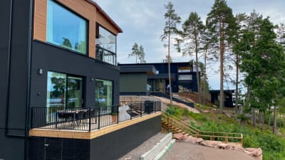 Flera lådformade, mörka hus i en sluttning.