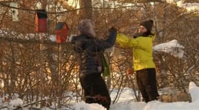 Lotta och Anne hänger upp resten av isterkorvarna i trädgrenarna