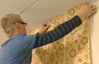 Sätter upp tapeten på väggen