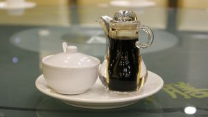 Soijakastikkeessa maistuu umami, sillä se on valmistettu fermentoimalla. Soijakastiketta lasikannussa pöydällä.