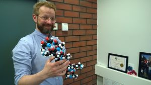iGem-tiimin ohjaaja professori Markus Linder. Markus Linder pitää kädessään molekyylimallia.